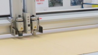 Close-up view of generative line art on paper using a mechanical plotter, showcasing industrial precision.
