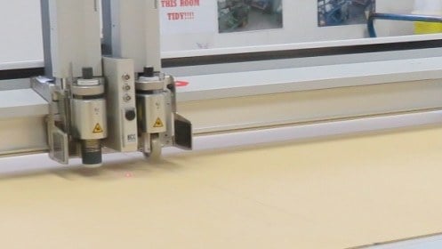 Close-up view of generative line art on paper using a mechanical plotter, showcasing industrial precision.